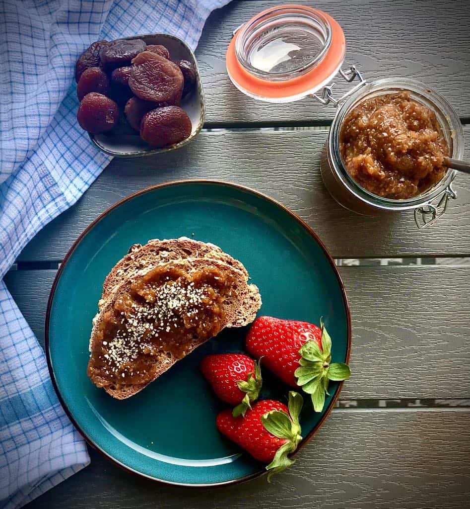 Jar of dried apricot chia jam next to a plate with toast.