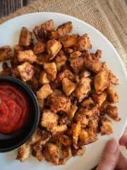 Tofu nuggets on a plate with a small bowl of ketchup.