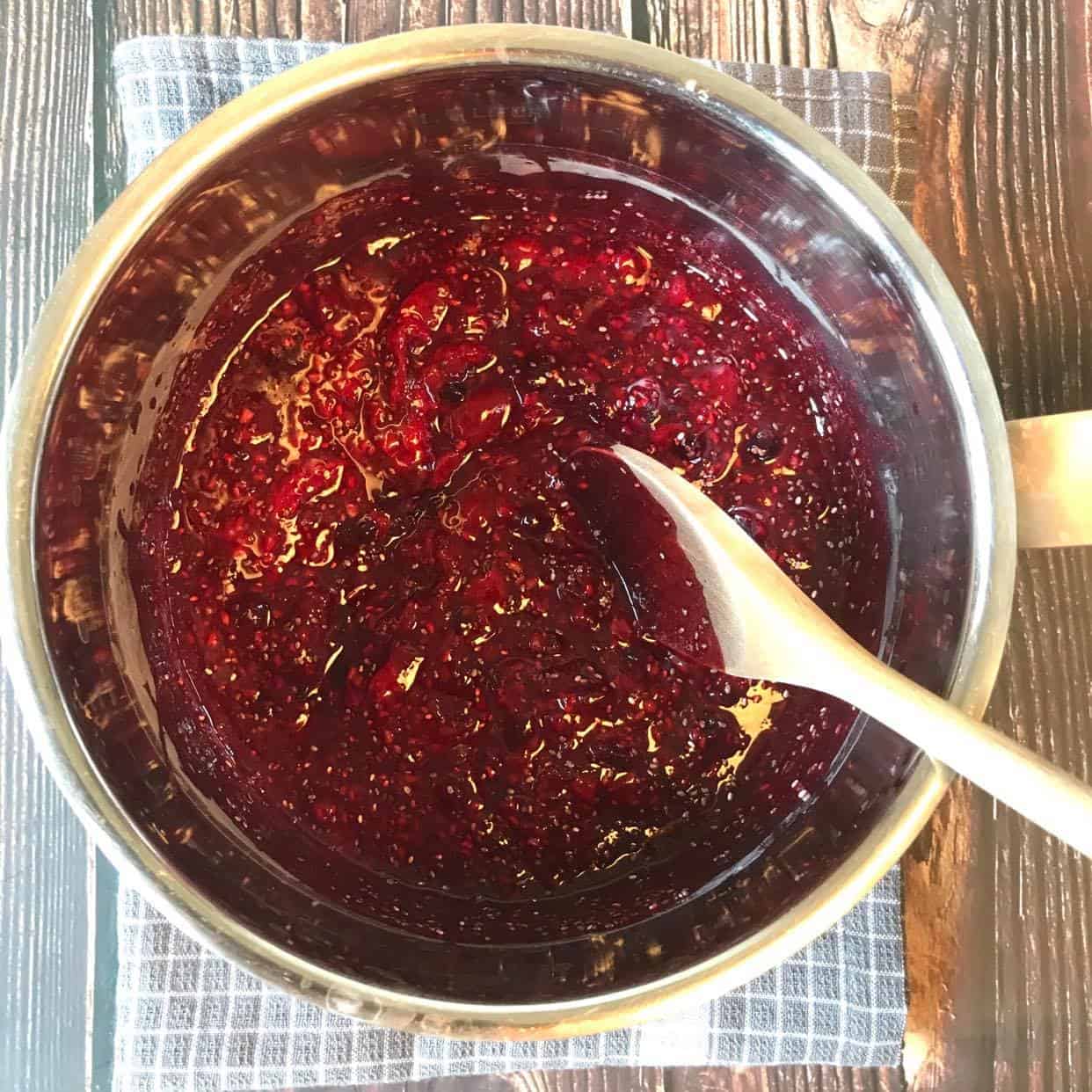 Mashed berries mixed with chia seeds in a pot.