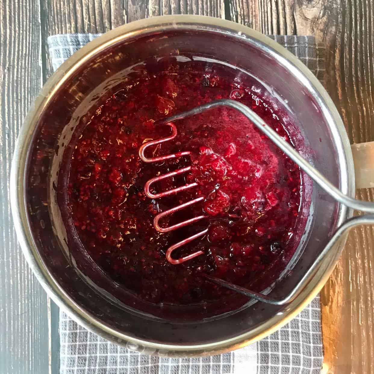 Mixed berries mashed in a pot.