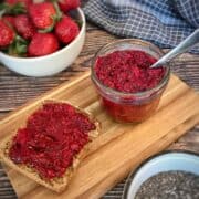 Chia berry jam in a jar next to a piece of bread with jam.