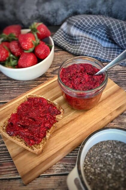 Chia berry jam in a jar next to a piece of bread with jam.