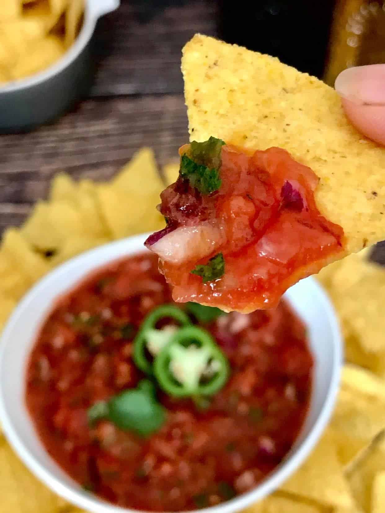 Bowl of the best restaurant style salsa with a chip dipping into it.