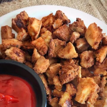 Tofu nuggets on a plate with a small bowl of ketchup.