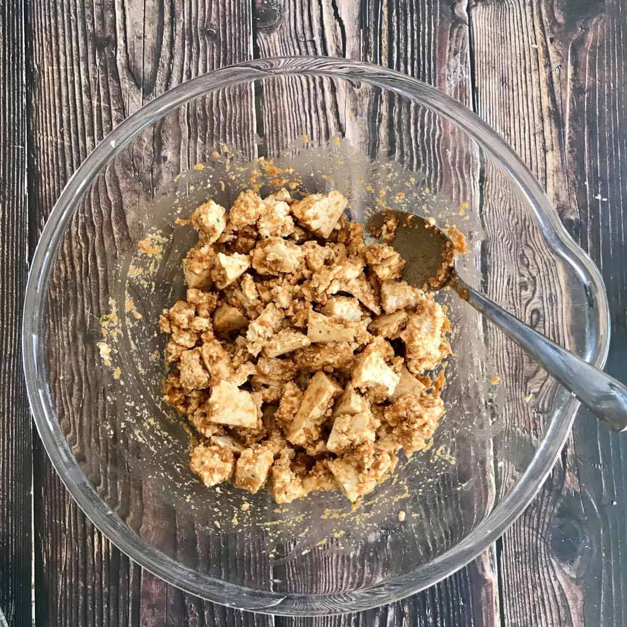 Tofu nuggets mixed with paste in a bowl.