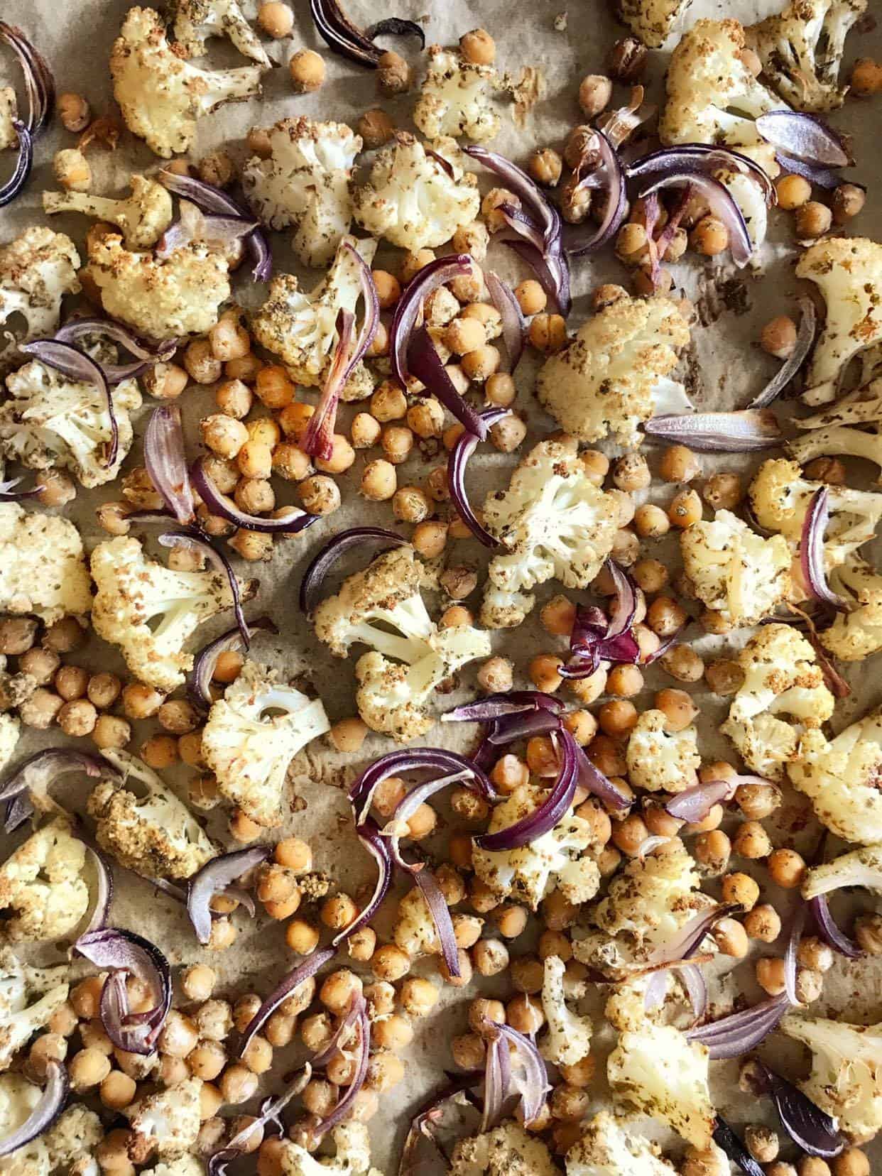 Cauliflower, chickpeas, and red onions on a sheet pan.