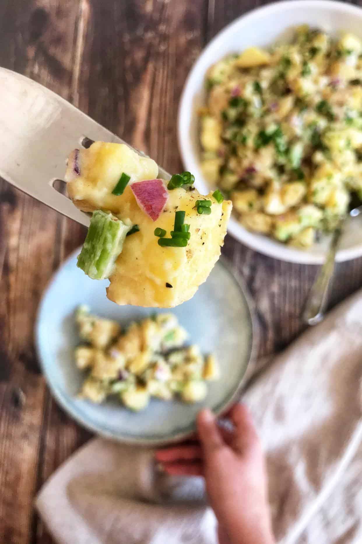 Fork holding up a bite of vegan potato salad.