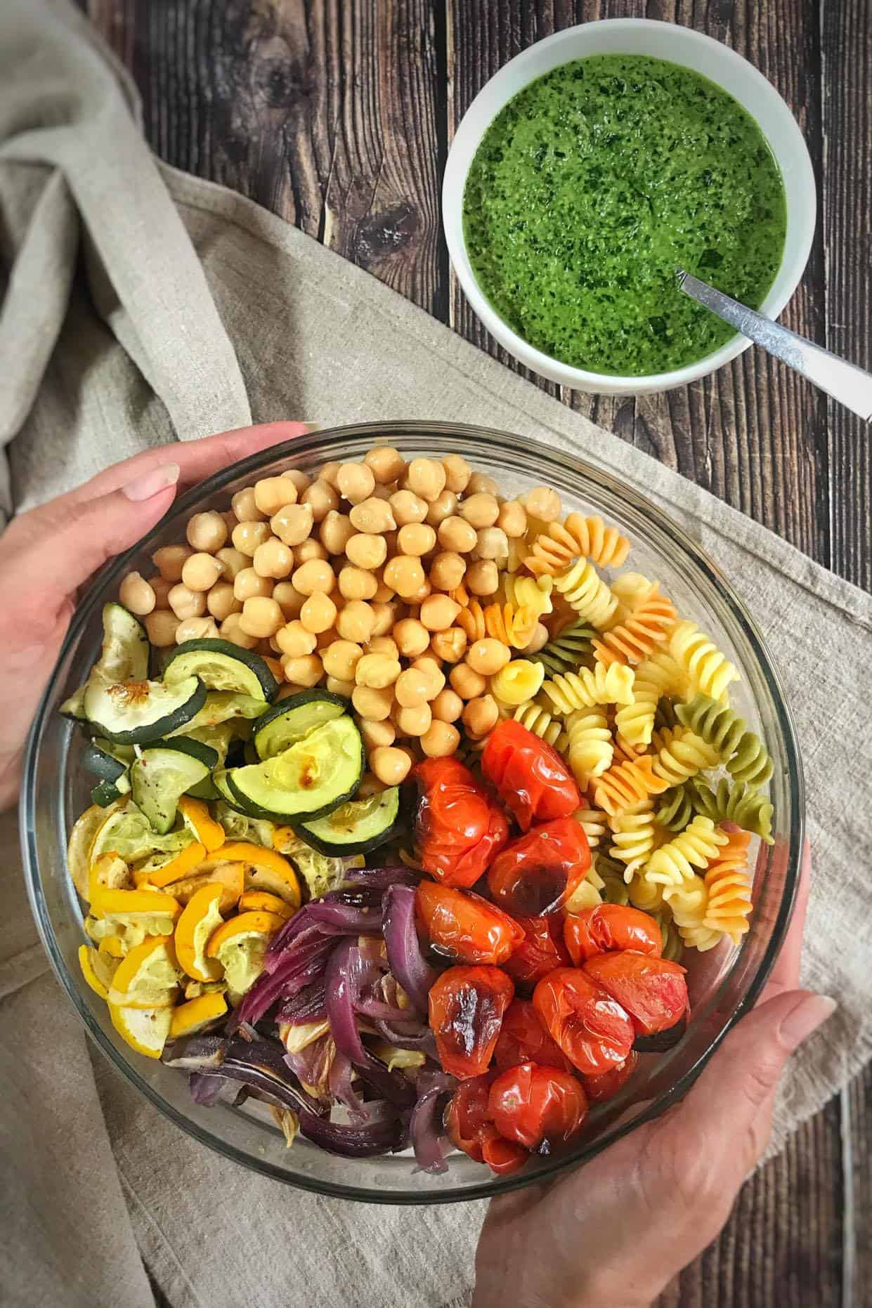 Vegan pesto pasta salad in a bowl next to a bowl of pesto.