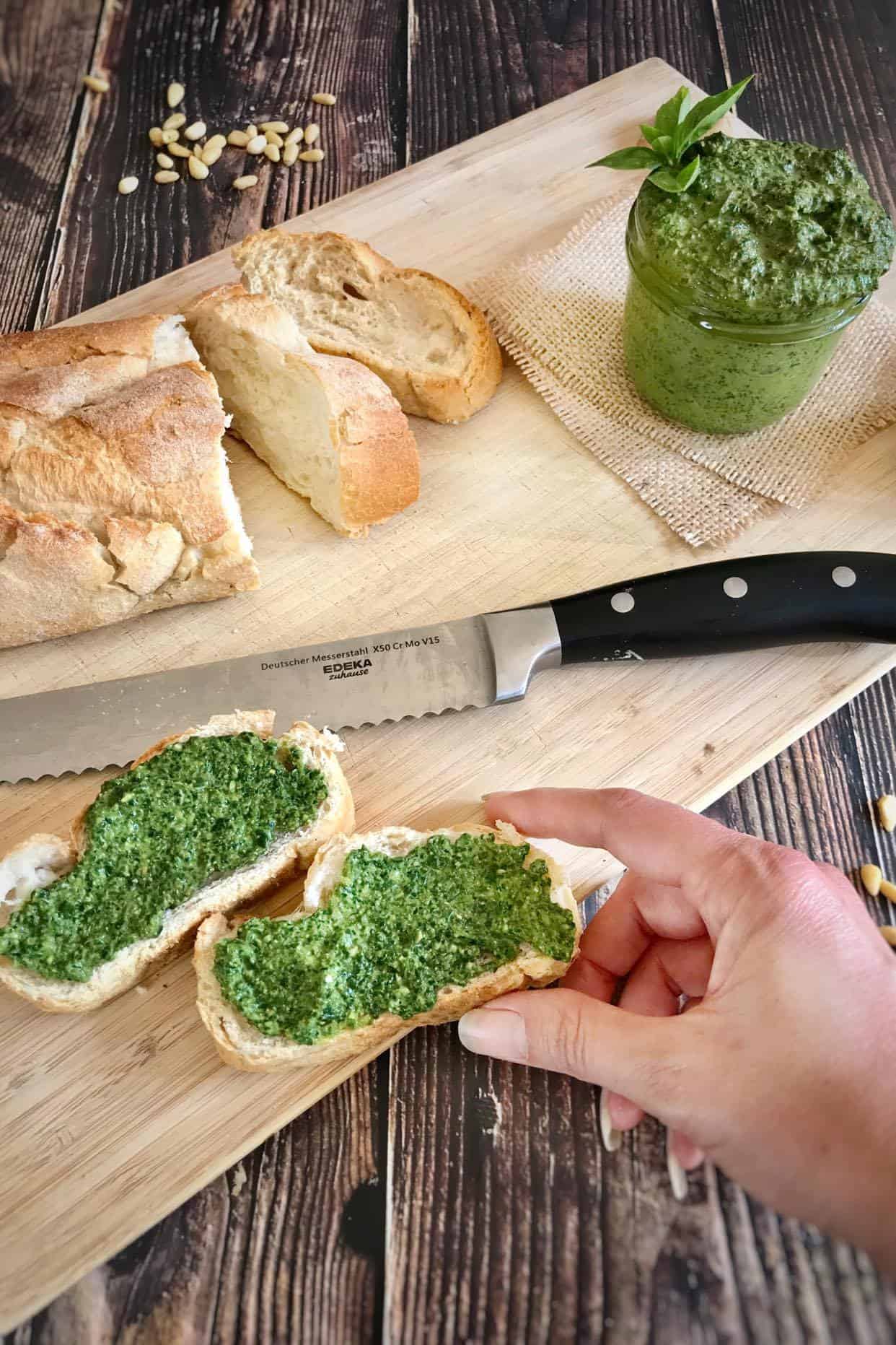 Vegan pesto sauce on cutting board with knife and bread.
