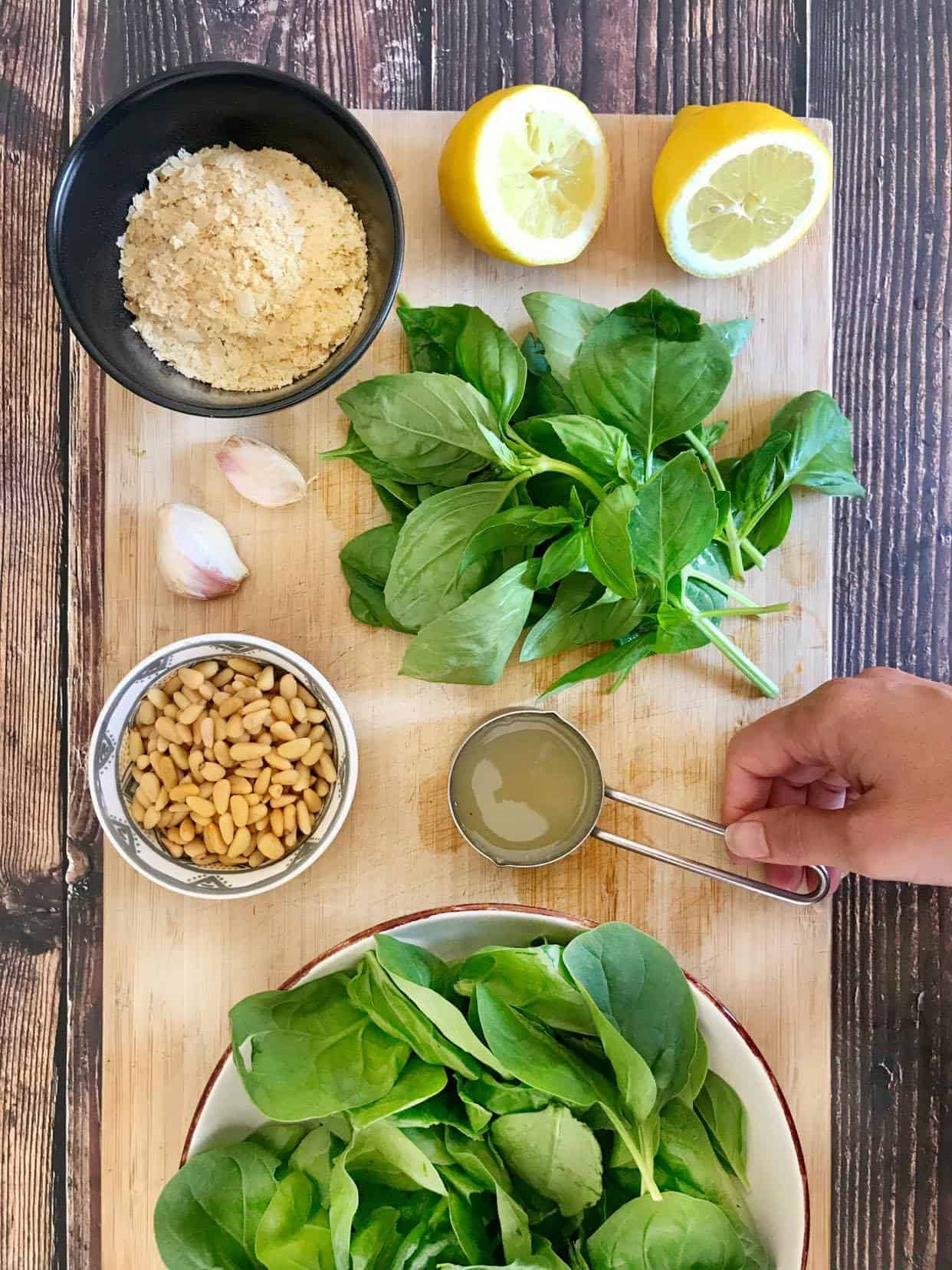 Oil-free vegan pesto ingredients (lemon juice, nutritional yeast, basil, garlic, pine nuts, aquafaba, and spinach).