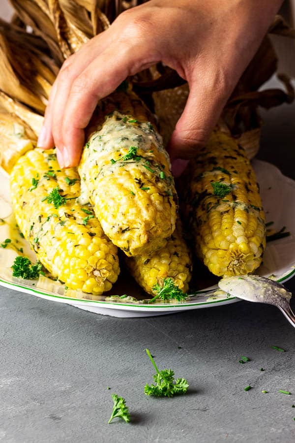 Hand picking up a piece of vegan corn on the cob.