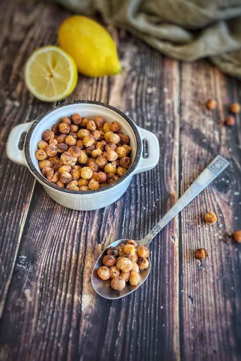 Roasted chickpeas in a bowl next to a spoon.