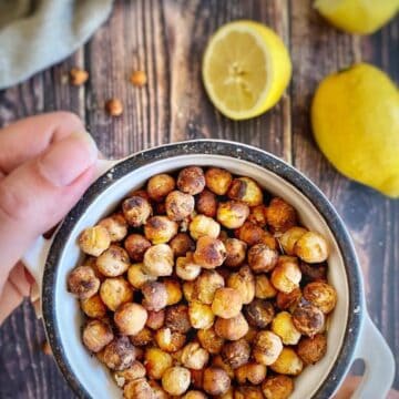 Hand holding a bowl of oil-free roasted chickpeas.