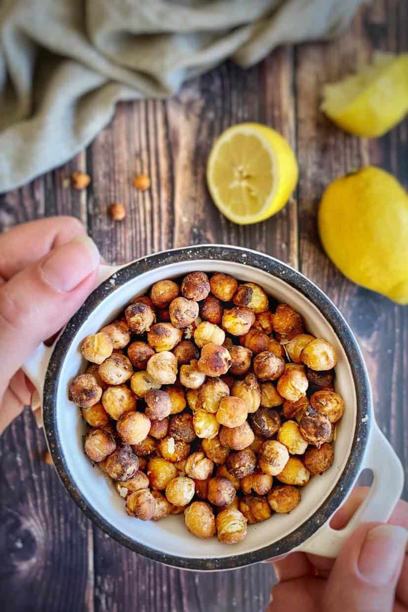 Hand holding a bowl of oil-free roasted chickpeas.