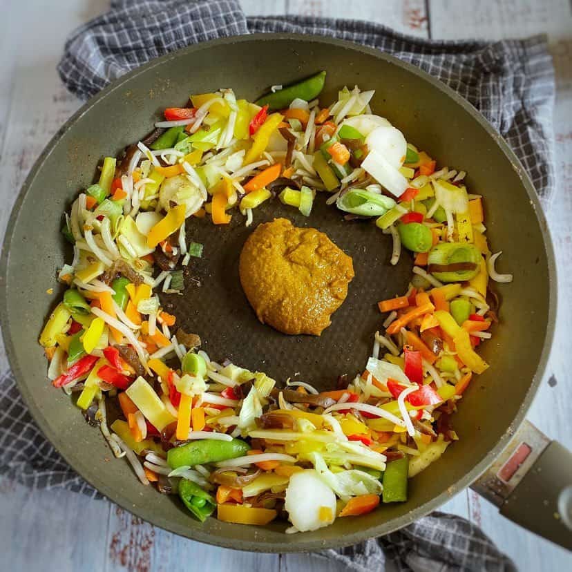 Vegetables and Thai curry paste in a skillet.