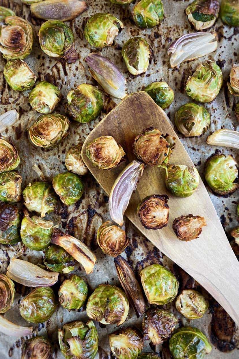 Wooden spatula lifting maple balsamic roasted Brussels sprouts.