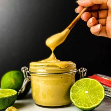 Vegan chipotle mayo in a jar with a hand lifting out a spoonful.