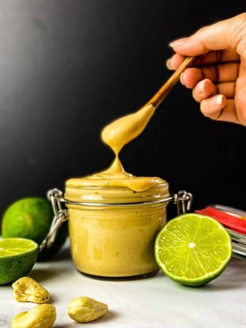 Vegan chipotle mayo in a jar with a hand lifting out a spoonful.