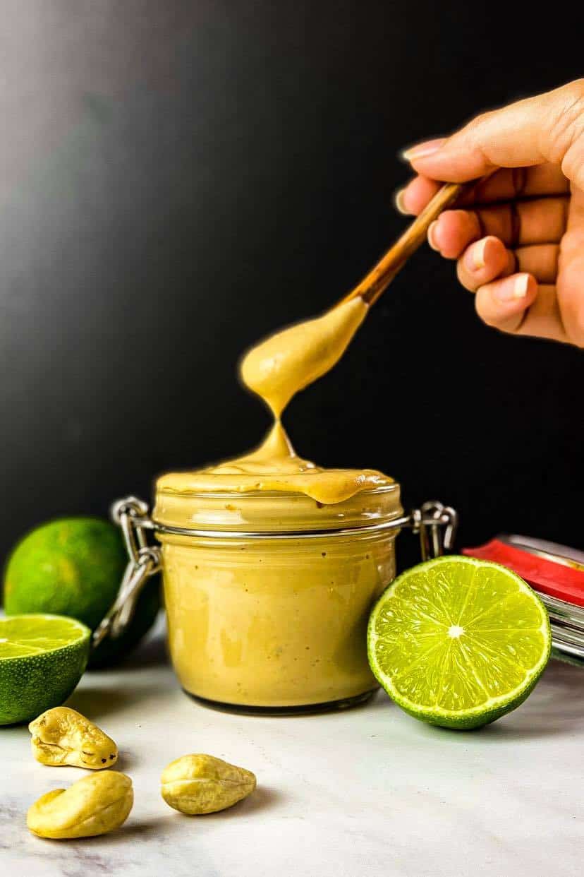 Vegan chipotle mayo in a jar with a hand lifting out a spoonful.