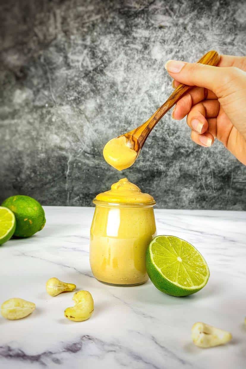 Hand lifting a spoonful of chipotle mayo from a jar.