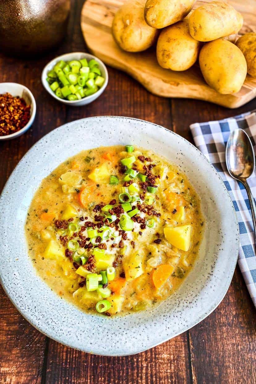 Vegan Potato Soup (creamy and chunky) in bowl with vegan bacon bits and green onion toppings.