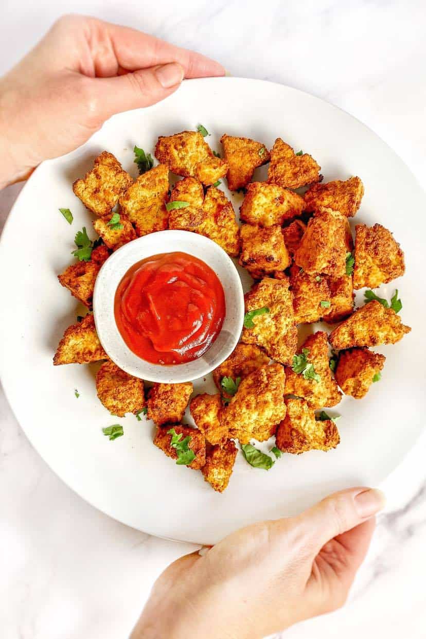 Air fryer tofu nuggets on a plate with ketchup.