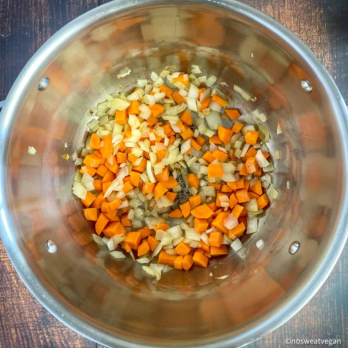 Diced onions and carrots cooking in a pot.
