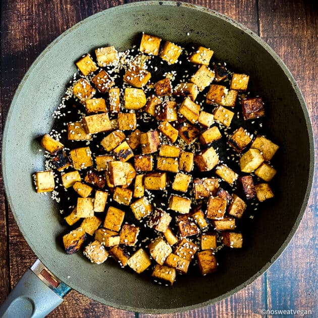 Tofu cooked in a skillet with sesame seeds.