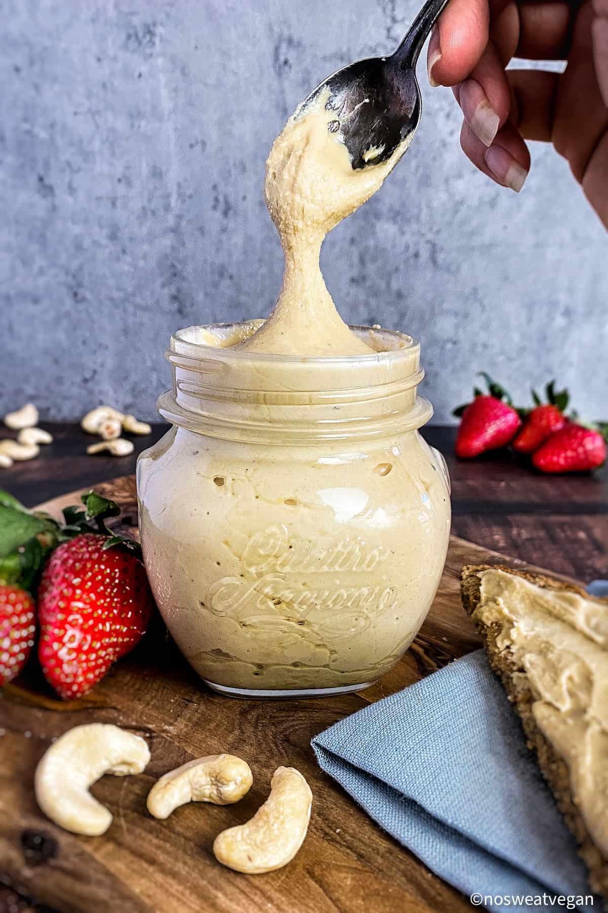 Cashew butter in a jar with toast and strawberries.