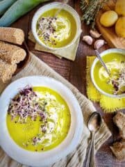 Leek and potato soup in bowls with herbs and bread.