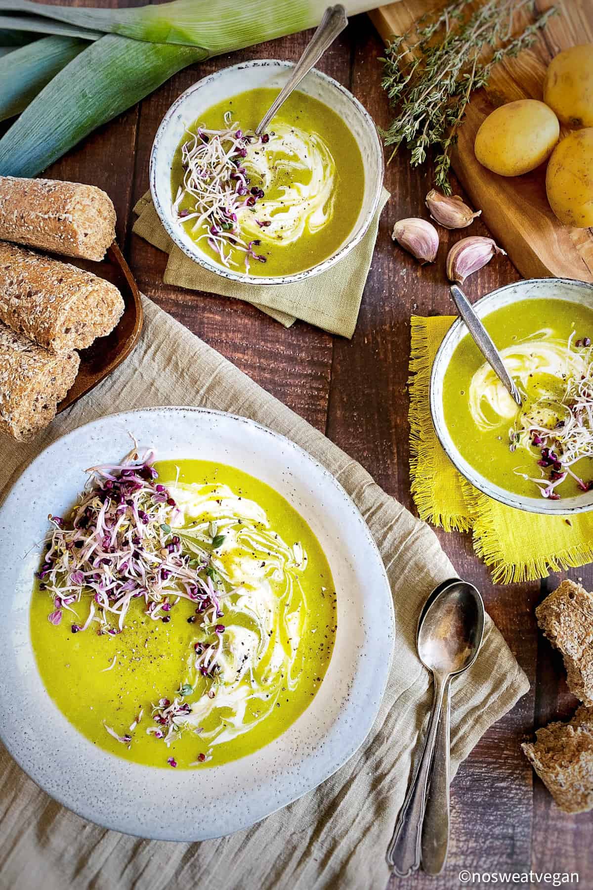 Leek and potato soup in bowls with herbs and bread.