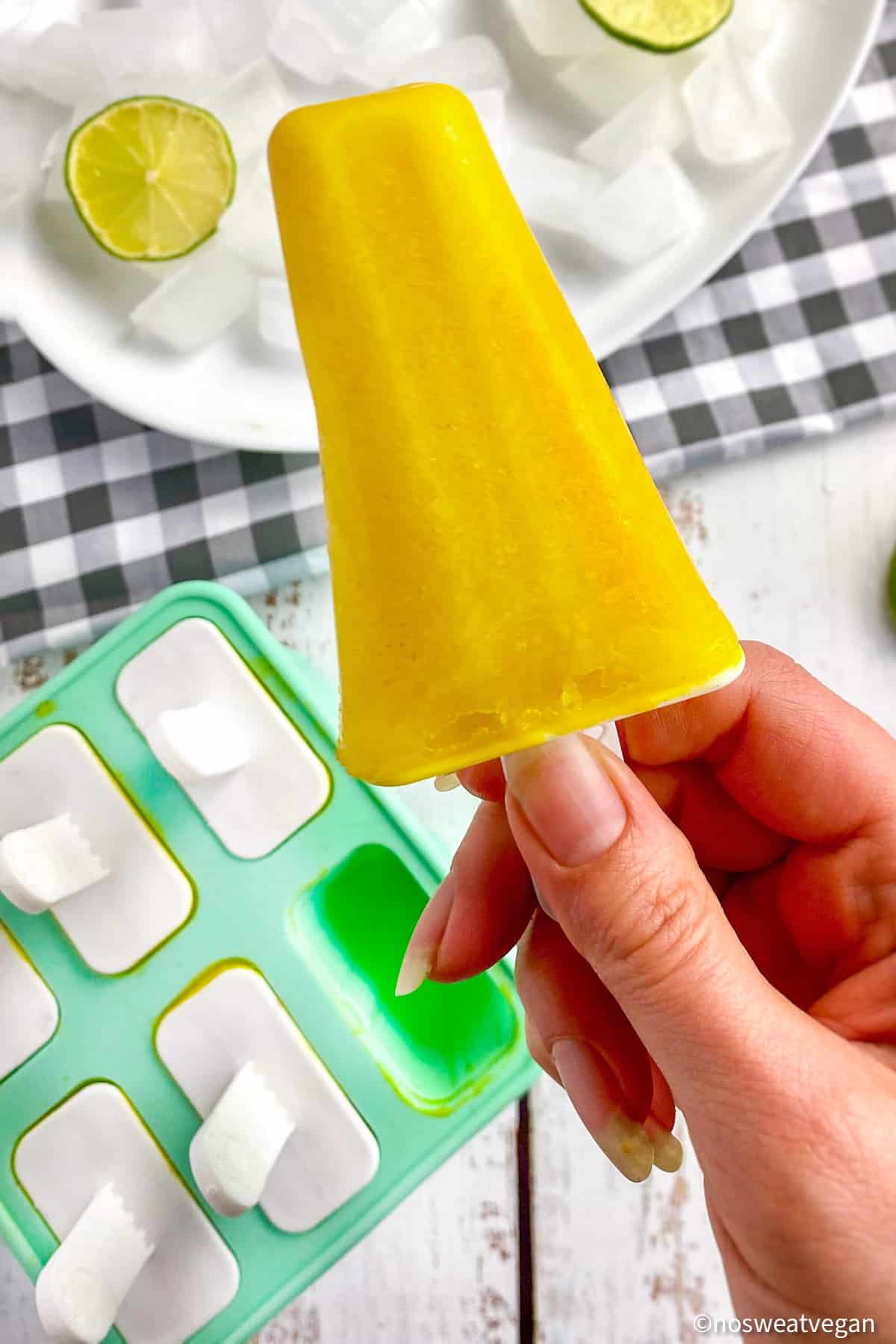 Mango ice pop held above a popsicle form.