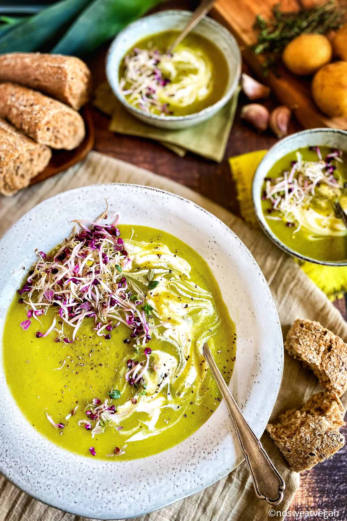 Vegan leek and potato soup in a bowl topped with vegan yogurt and microreens.