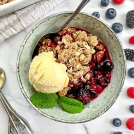 Vegan berry crumble in bowl with ice cream.