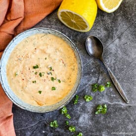 Best vegan remoulade sauce in a bowl with lemons and parsley on the side.