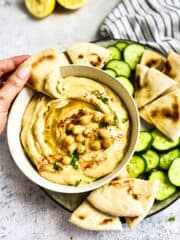Hand dipping pit into oil-free hummus.