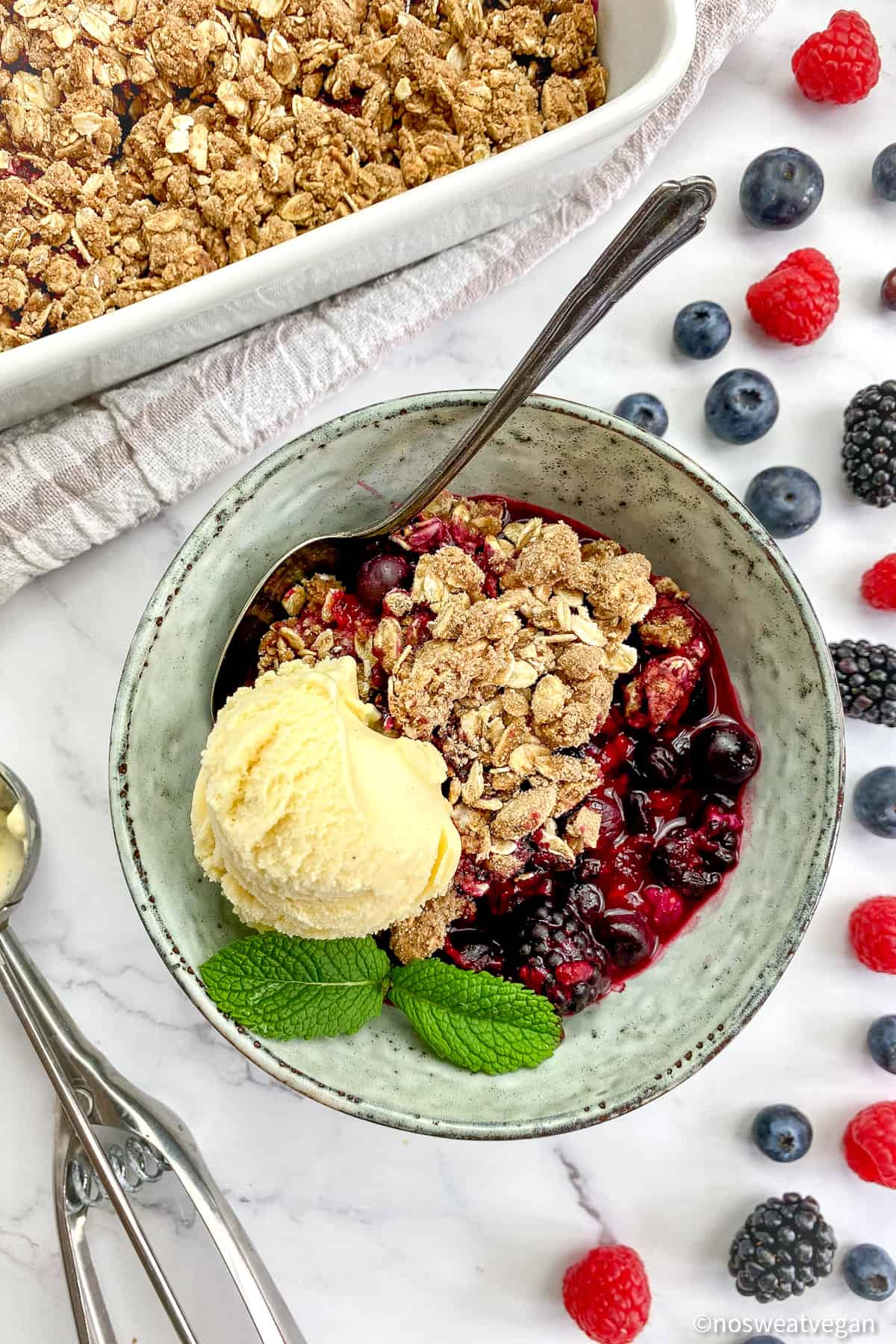 Vegan berry crumble in a bowl with a scoop of ice cream.