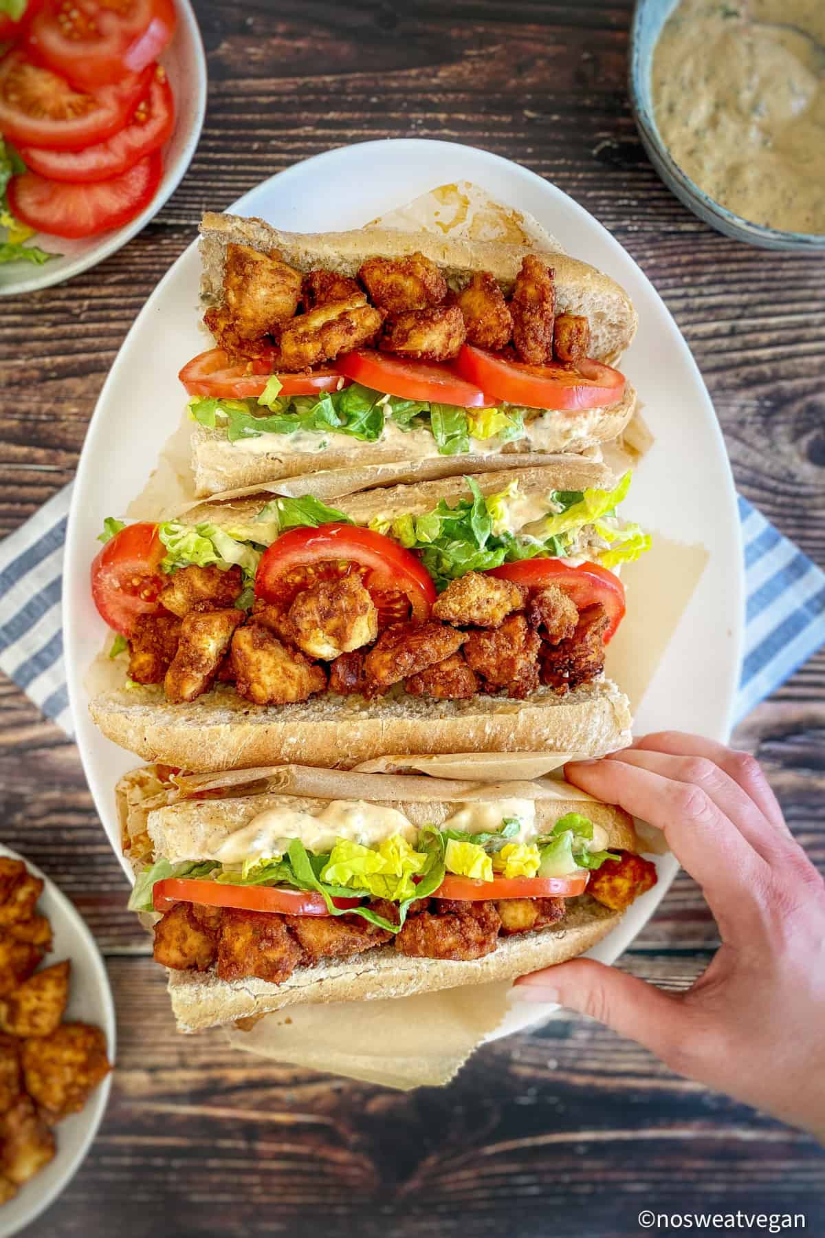Three vegan cajun Po Boy sandwiches on a plate.