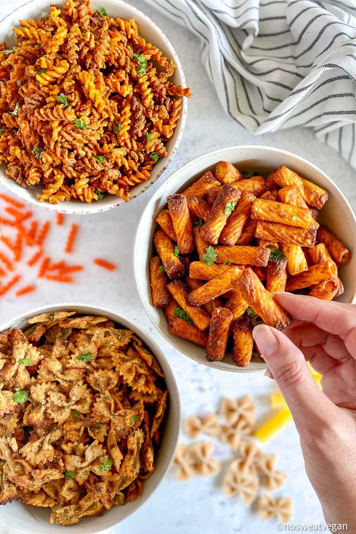 Three bowls with pasta chips and a hand holding one of the chips.