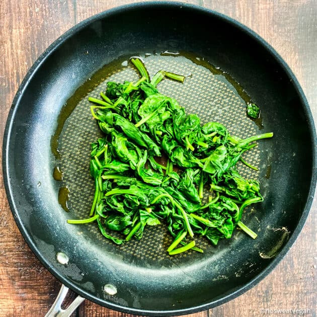 Cooked spinach in skillet.