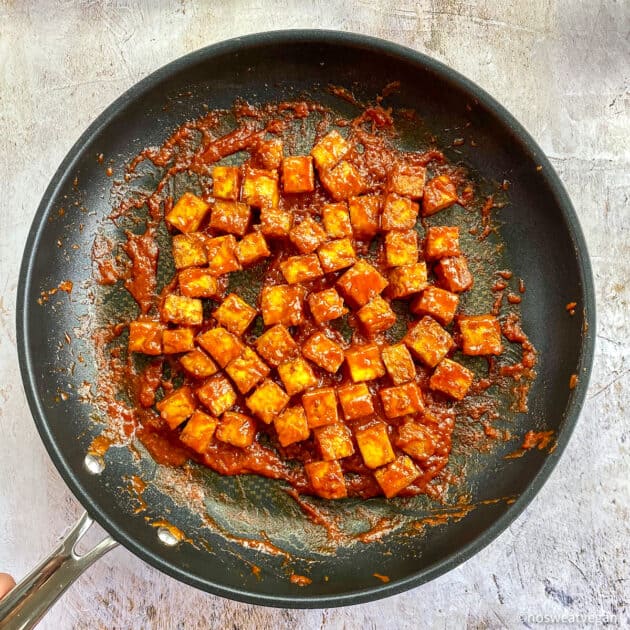 Tofu mixed with Korean sauce in skillet.