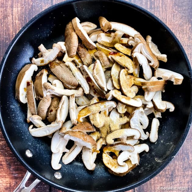 Uncooked Shiitake mushrooms in skillet.