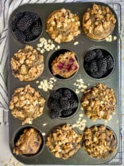 Vegan blackberry muffins in muffin tin with blackberries.