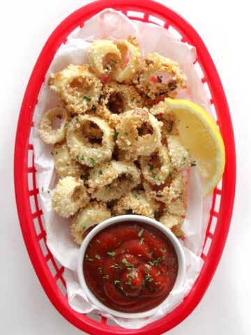 Vegan air fryer calamari in a basket with sauce.