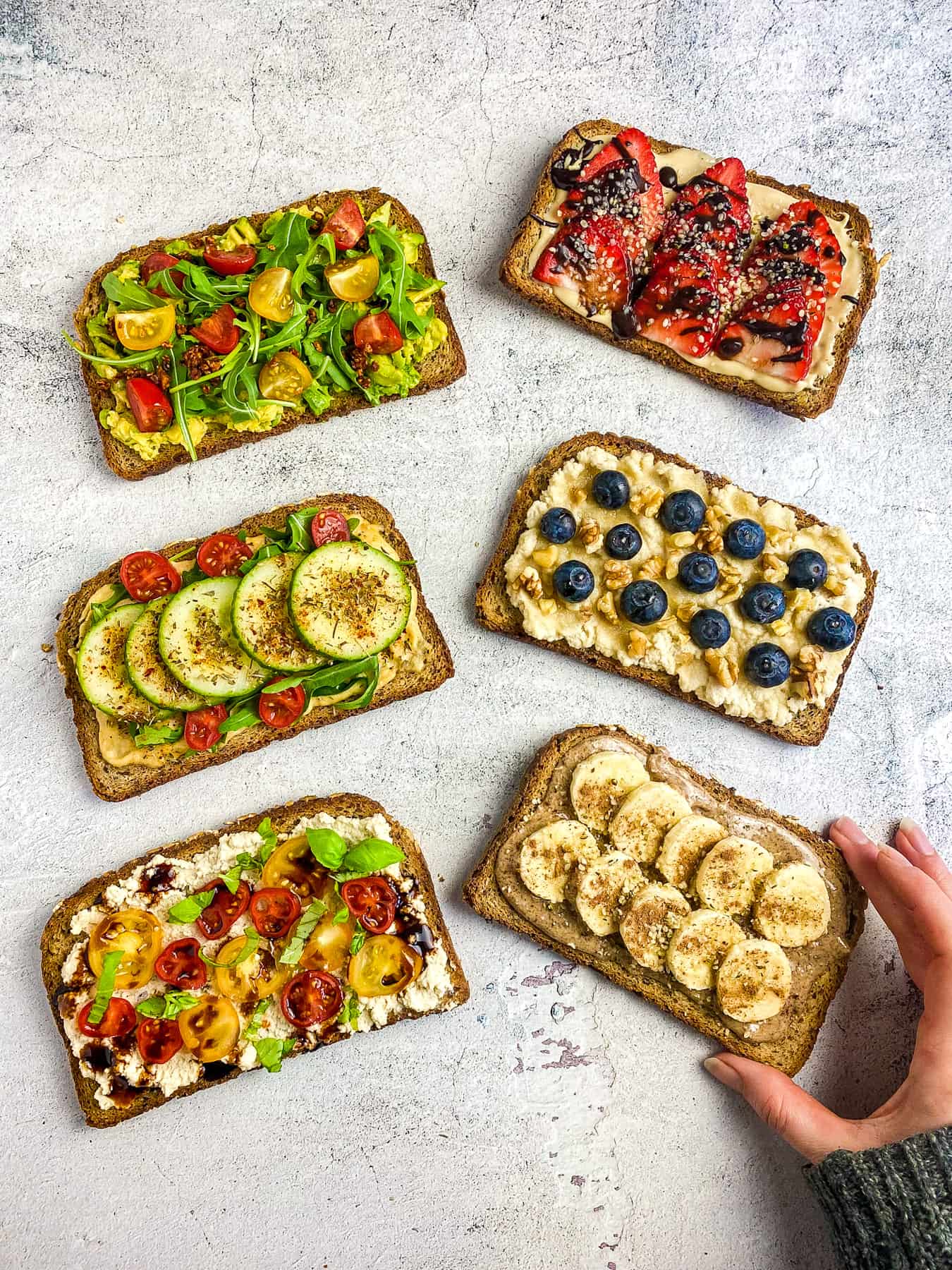 6 vegan toast ideas with hand about to pick one up.