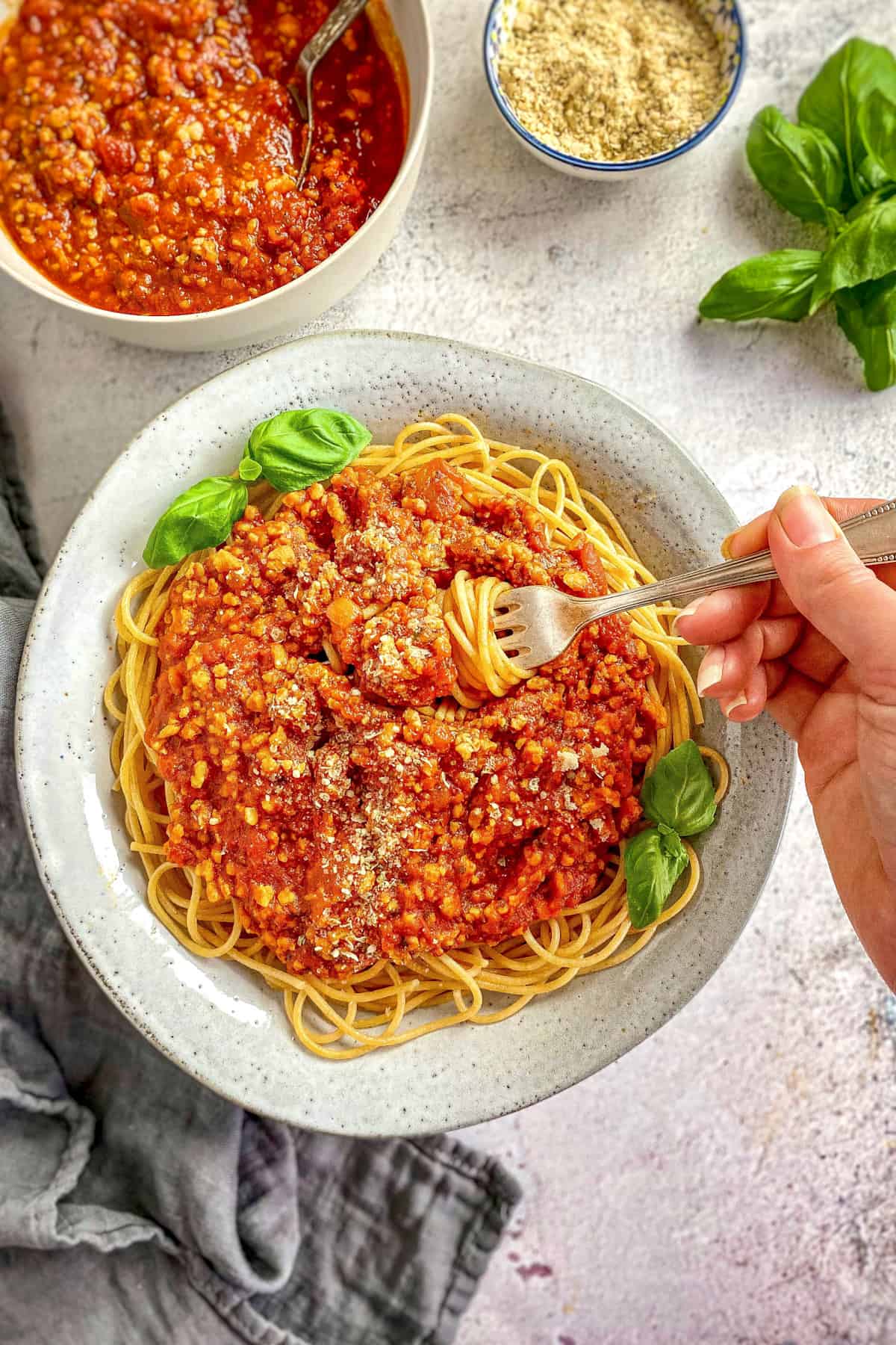 Hand holding a fork in a plate of vegan spaghetti.