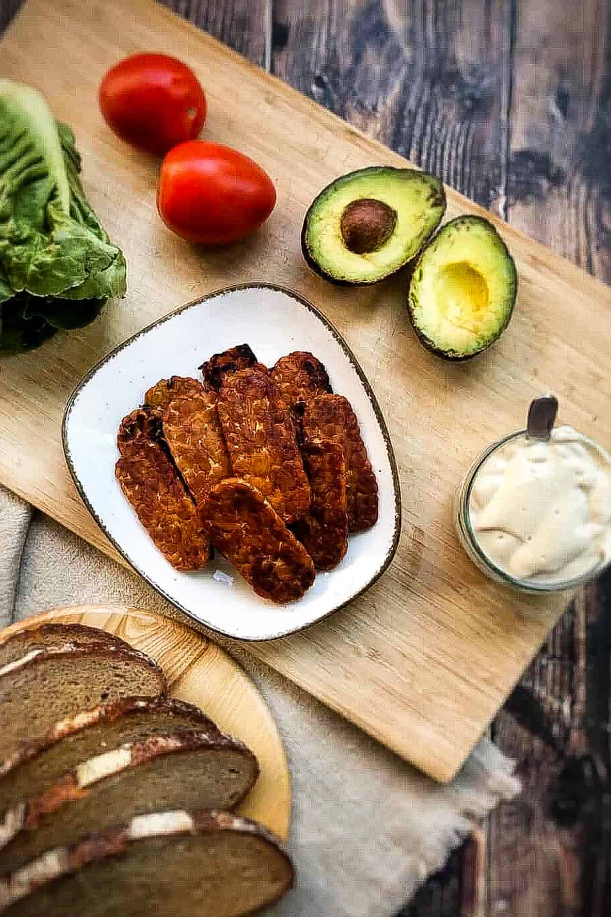 Tempeh bacon on plate surrounded by ingredients.