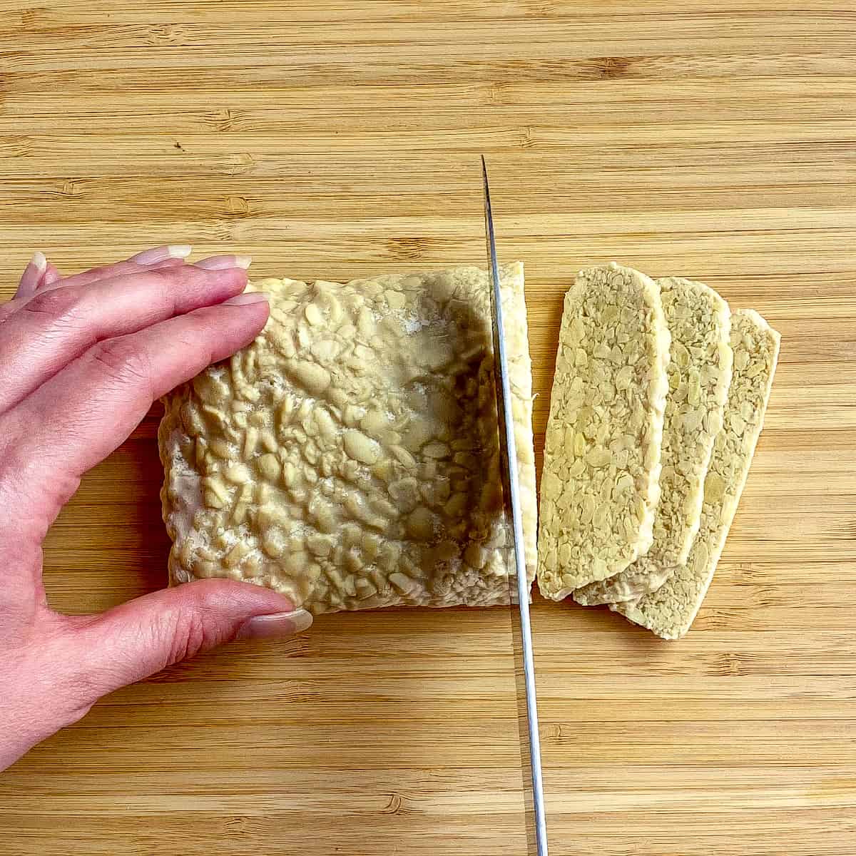 Hand slicing tempeh.