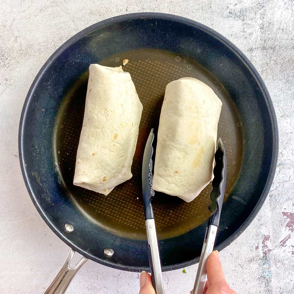 Two breakfast burritos in skillet.