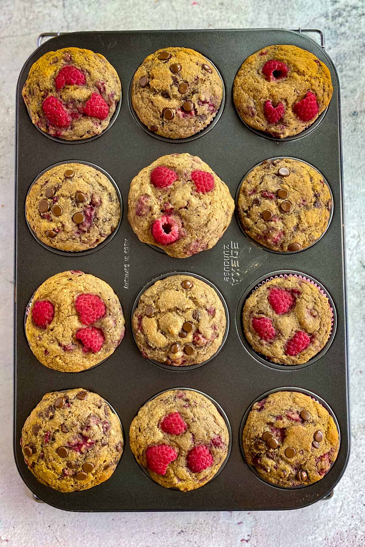 Cooked vegan raspberry muffins in a tin.